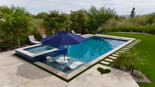 Pool and spa with umbrella, in-water loungers, and heart turf