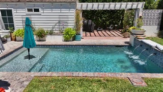 Geometric pool with brick coping, spa spillover, and shaded pergola lounge